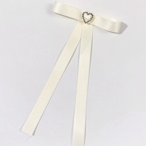 Dettaglio del fiocco in raso crema con strass a cuore e nappine lunghe eleganti