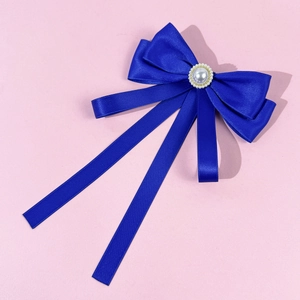 Detailed view of dark blue satin bow brooch with pearl center and elegant long ribbons