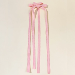 Dettaglio dei fermagli per capelli con fiocco in raso rosa e lunghi nastri ondulati