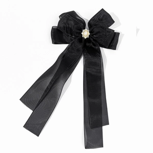 Détail d'une pince à cheveux noire avec rubans satinés, résille, perles et strass