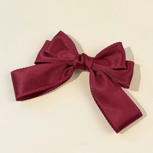 Détail du nœud à cheveux en satin bordeaux avec d'élégants bords en dentelle festonnée