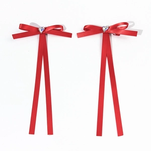 Détail de nœuds à cheveux en satin rouge avec strass coeur et longs rubans de soie