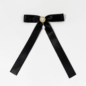 Close-up of black satin bow hair clip with elegant pearl drop and golden bead trim