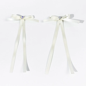 Détail de barrettes nœuds en satin blanc avec cristal cœur violet et rubans longs