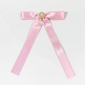 Close-up of pink satin bow hair clip with vintage pearl center and dangling teardrop pearl