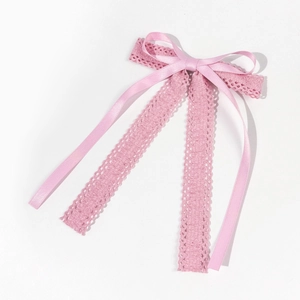 Détail d'un nœud en soie rose avec rubans en dentelle et motifs floraux ajourés délicats