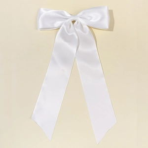 Dettaglio di un grande fiocco per capelli in raso bianco con lunghi nastri eleganti