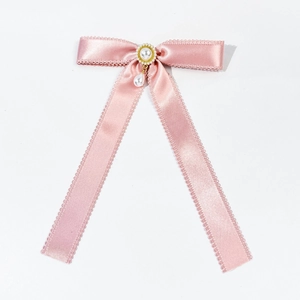 Detailed close-up of a pink satin bow hairpin with lace edges and a pearl drop pendant