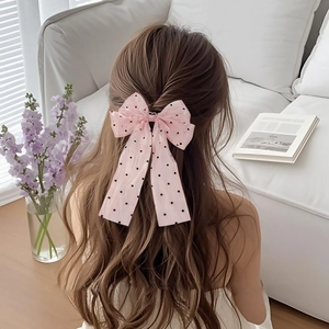 Detailed close-up of a pink tulle bow hair clip with polka dots and heart-shaped rhinestone