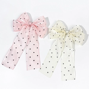 Detail of pink and cream polka dot bow hair clips with elegant heart crystal accents