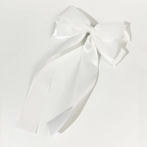 Détail d'une pince à cheveux à nœud en satin blanc avec de longs rubans fluides