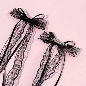 Paire de nœuds en dentelle noire élégants avec rubans longs sur fond rose