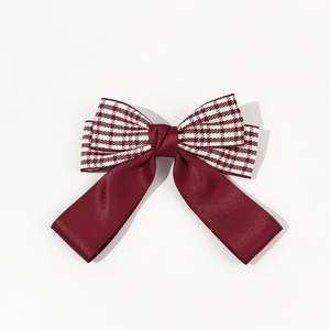 Detailed view of the houndstooth and burgundy satin bow hair clip with elegant fabric textures