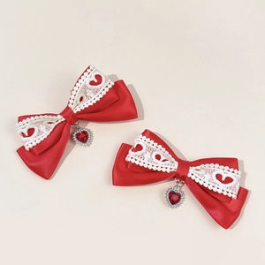 Detail of red bow hair clips with white heart lace and hanging heart gems for girls