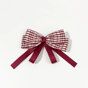 Detail of burgundy houndstooth bow hair clip with layered satin ribbons and vintage texture