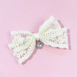 Detailed embroidery on white lace bow hair clip featuring a heart crystal pendant