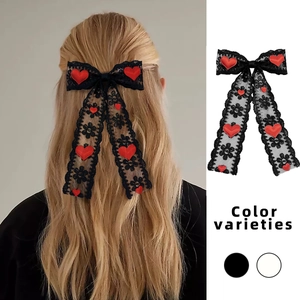 Détail d'un nœud en dentelle noire avec cœur rouge et longs rubans pour cheveux