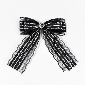 Detail of black lace hair clip with heart rhinestone and ribbon script pattern