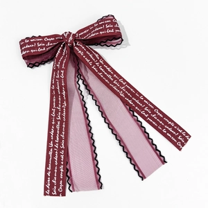 Close-up of wine red lace bow hair clip featuring French script print and mesh detail