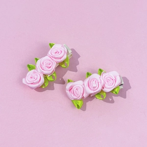 Gros plan détaillé de barrettes à cheveux fleurs en satin rose faites à la main