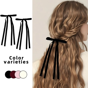Detail view of elegant black velvet bow hair clip with long ribbons on model's hair
