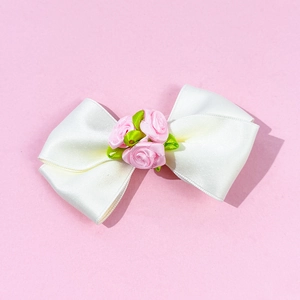 Détail d'une barrette à cheveux nœud en satin blanc avec roses en tissu rose et feuilles
