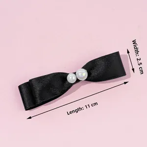 Détail du nœud élégant en satin noir avec perles blanches, taille 11 cm par 2,5 cm