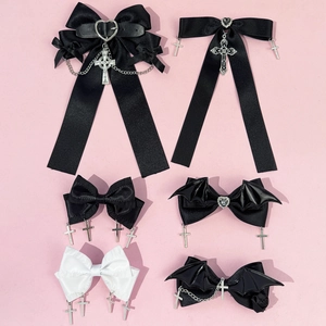 Gothic bow hair clips set with heart buckles and silver metal crosses on pink background