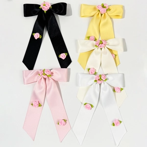 Détail de nœuds en satin ornés de roses en soie faites main et de broderies de feuilles