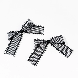 Vue détaillée des pinces à cheveux à nœuds à carreaux noirs et blancs avec dentelle