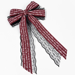 Detail of burgundy satin bow with black lace trim and white handwritten script print