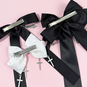 Gothic bow hair clips set with metal crosses and chains on a pink background