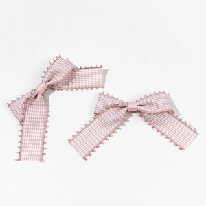 Détail de barrettes à cheveux à nœuds vichy rose et blanc avec bords à franges