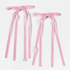 Set of two elegant pink velvet bow hair clips with long streamers on a white background