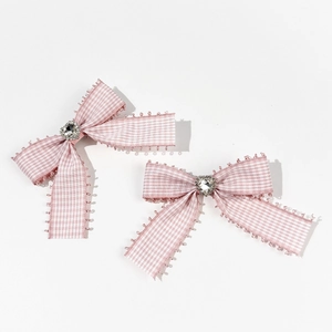 Détail de barrettes à nœud vichy rose avec centre en cristal cœur et bordure en dentelle