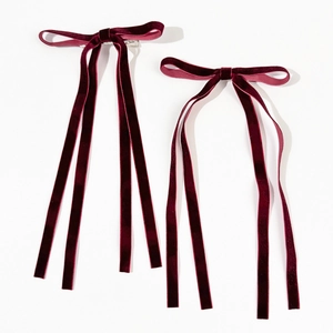 Detail of two wine red velvet bow hair clips with long elegant hanging streamers