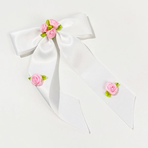 Détail d'un nœud en satin blanc avec roses en tissu rose et longs rubans fluides