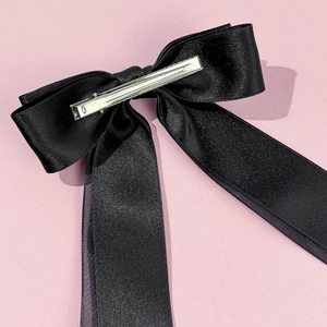 Elegant double-layered black mesh bow hair clip with long ribbons on pink background