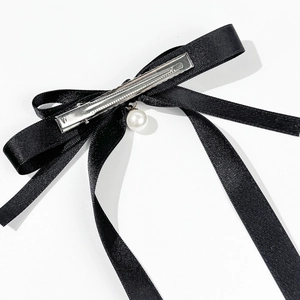 Detailed macro view of black satin bow hair clip featuring an elegant pearl pendant
