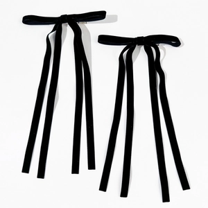Detail view of two black velvet bow hair clips with long elegant streaming ribbons