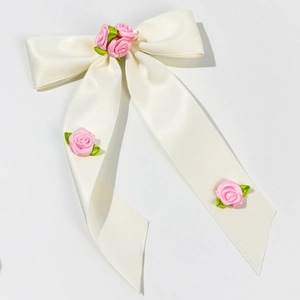 Détail de barrette nœud en soie avec roses en tissu rose et longs rubans de satin crème