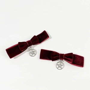 Détail de barrettes à nœuds en velours rouge foncé avec breloque étoile en argent