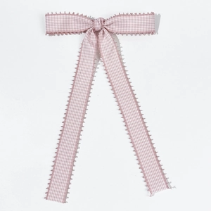 Detail of pink gingham fabric bow hairclip with wavy pom-pom trim and long ribbon tails