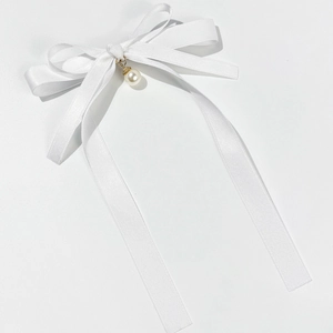 Detailed macro view of white ribbon bow with elegant pearl and gold metal base