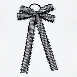 Detail of checkered bow hair clip with long ribbons and delicate black lace trim