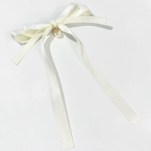 Close-up of white satin bow hair clip with an elegant faux pearl and gold pendant detail