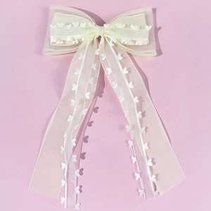 Détail de la barrette nœud en organza ivoire avec dentelle cœur et longs rubans