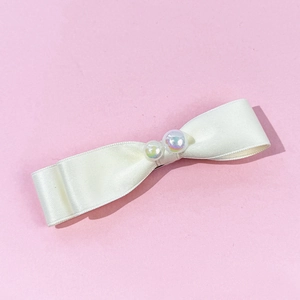 Détail de la pince à cheveux en satin crème avec napperon de perles irisées et clip en métal