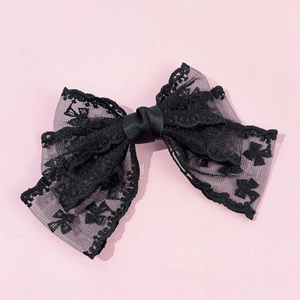 Detail of elegant black lace bow hair clip with intricate floral patterns and mesh texture
