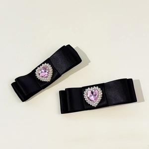 Détail macro de barrettes à nœud en soie avec strass cœur rose et perles